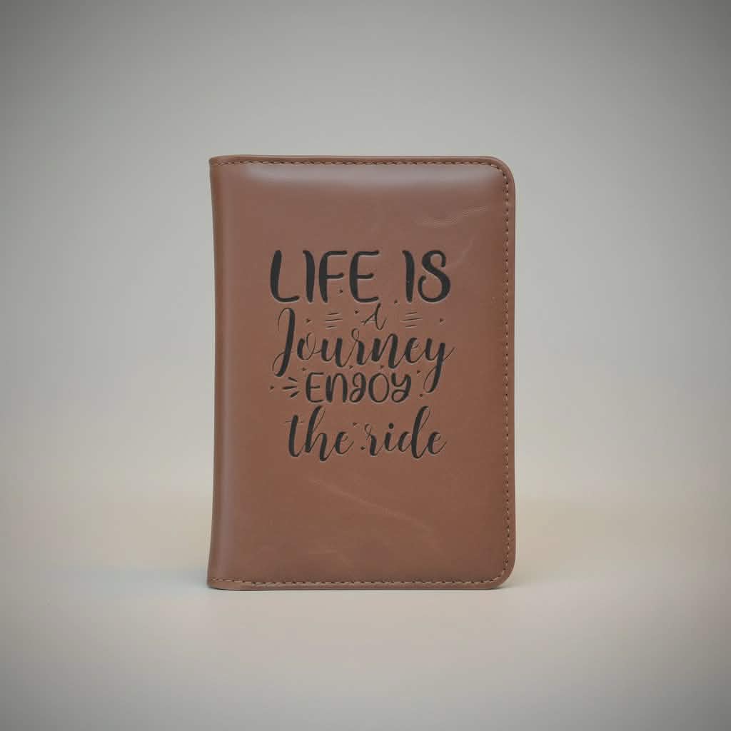 Brown leather notebook with 'Life is a Journey, Enjoy the Ride' text on a light gray background