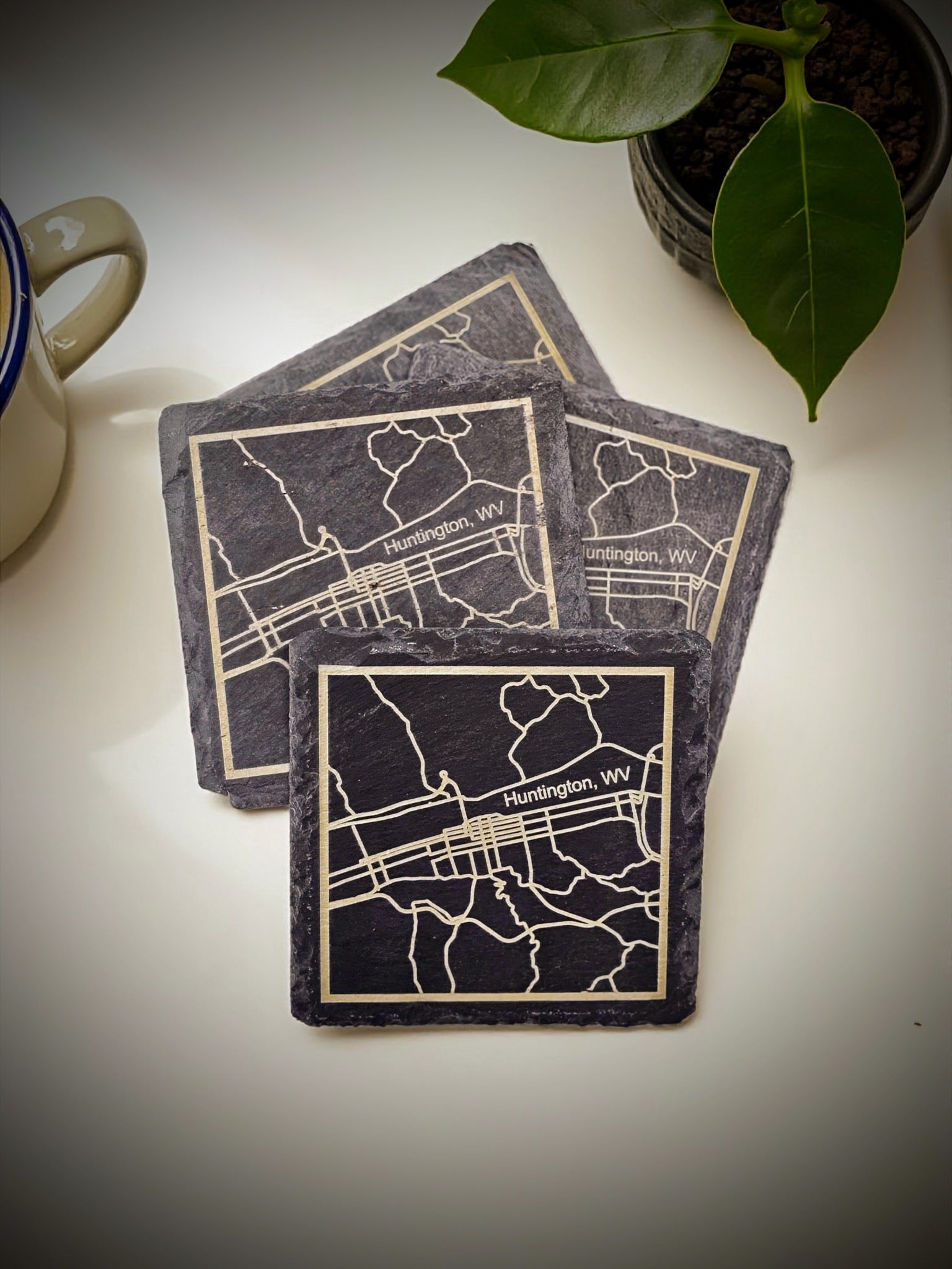 Three coasters with map designs on a light surface with a plant in the background.