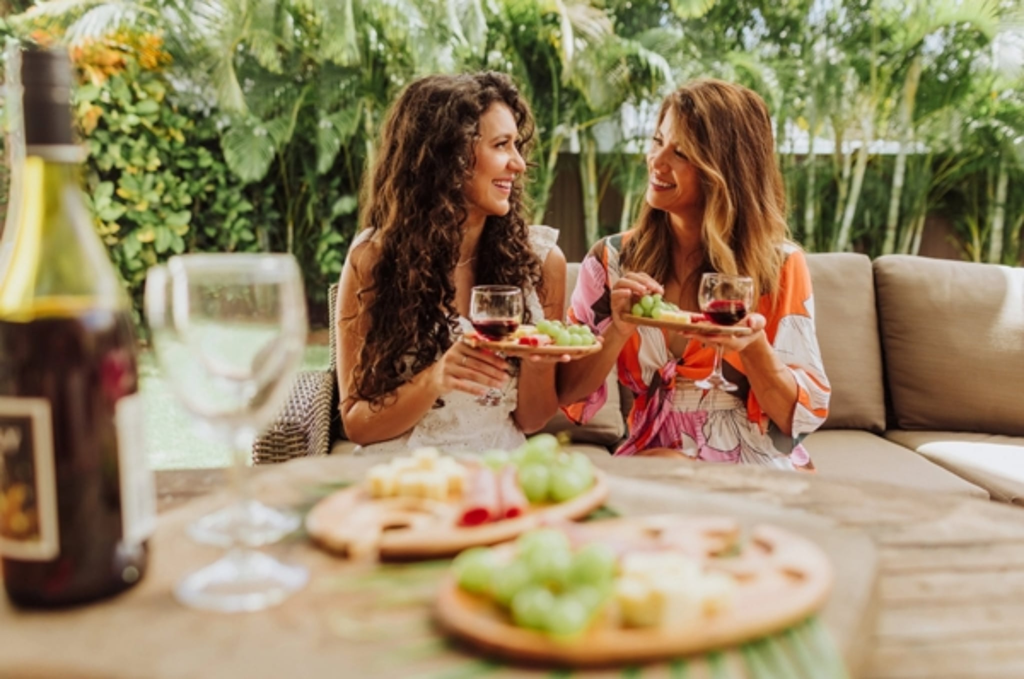 Girlfriends drinking wine with wine appetizer plates in foreground