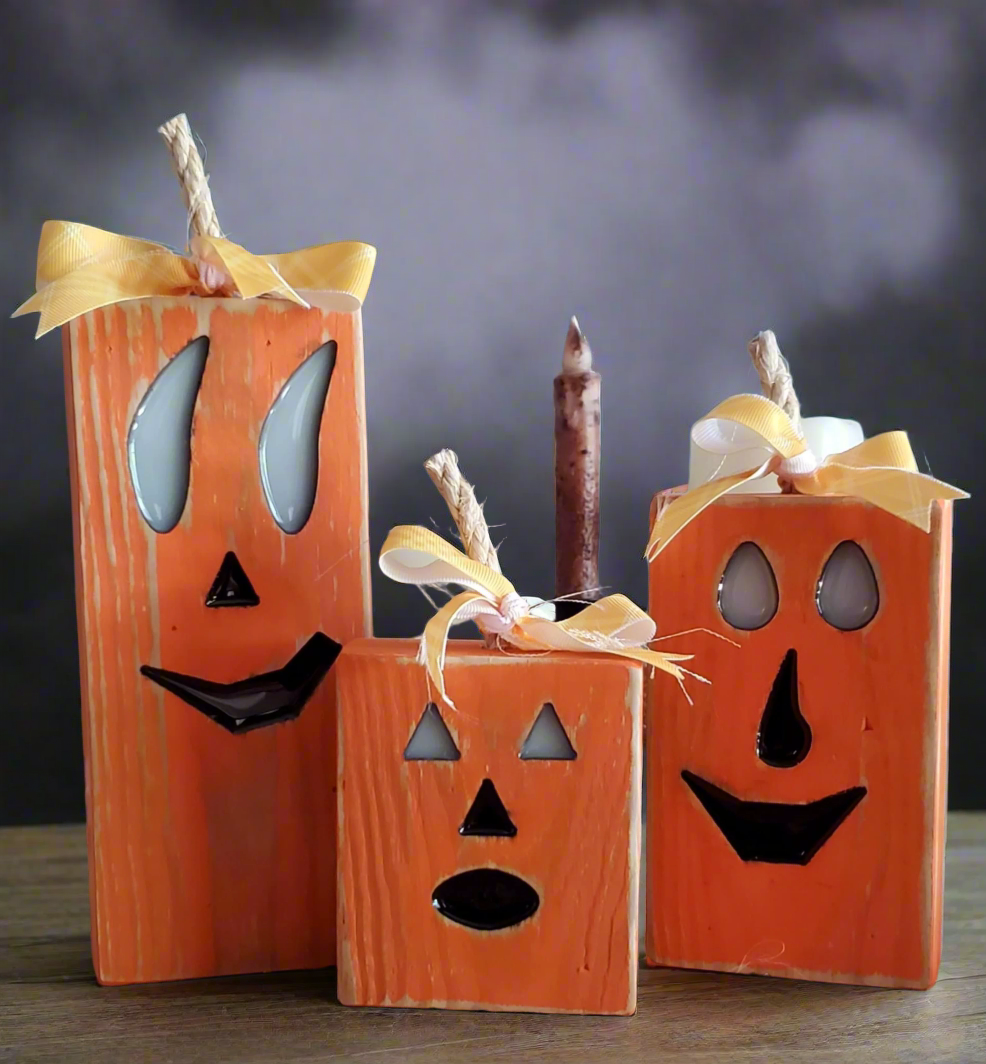 Wooden pumpkin decorations with faces and candles on a dark background