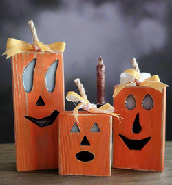 Wooden pumpkin decorations with faces and candles on a dark background