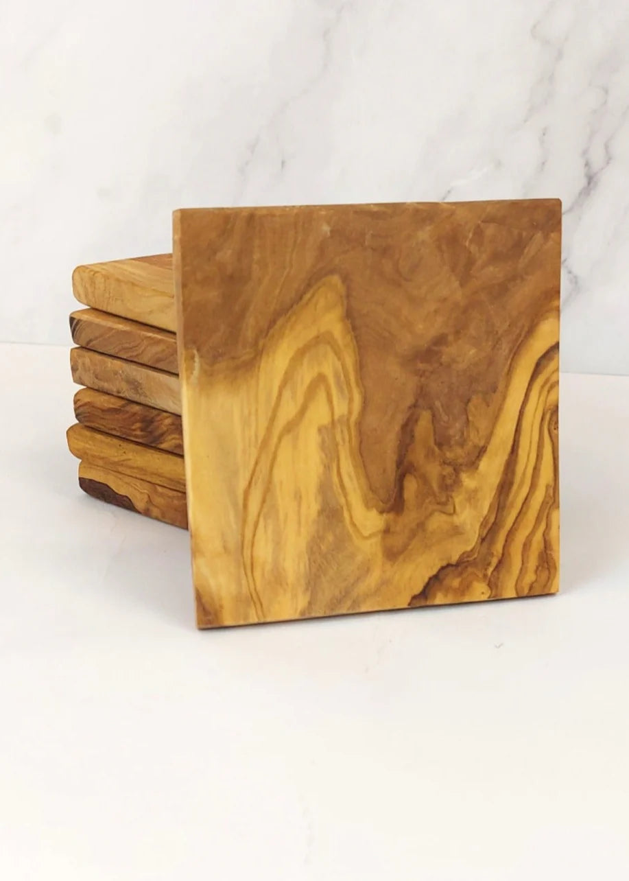 Several square olive wood coasters on a marble surface