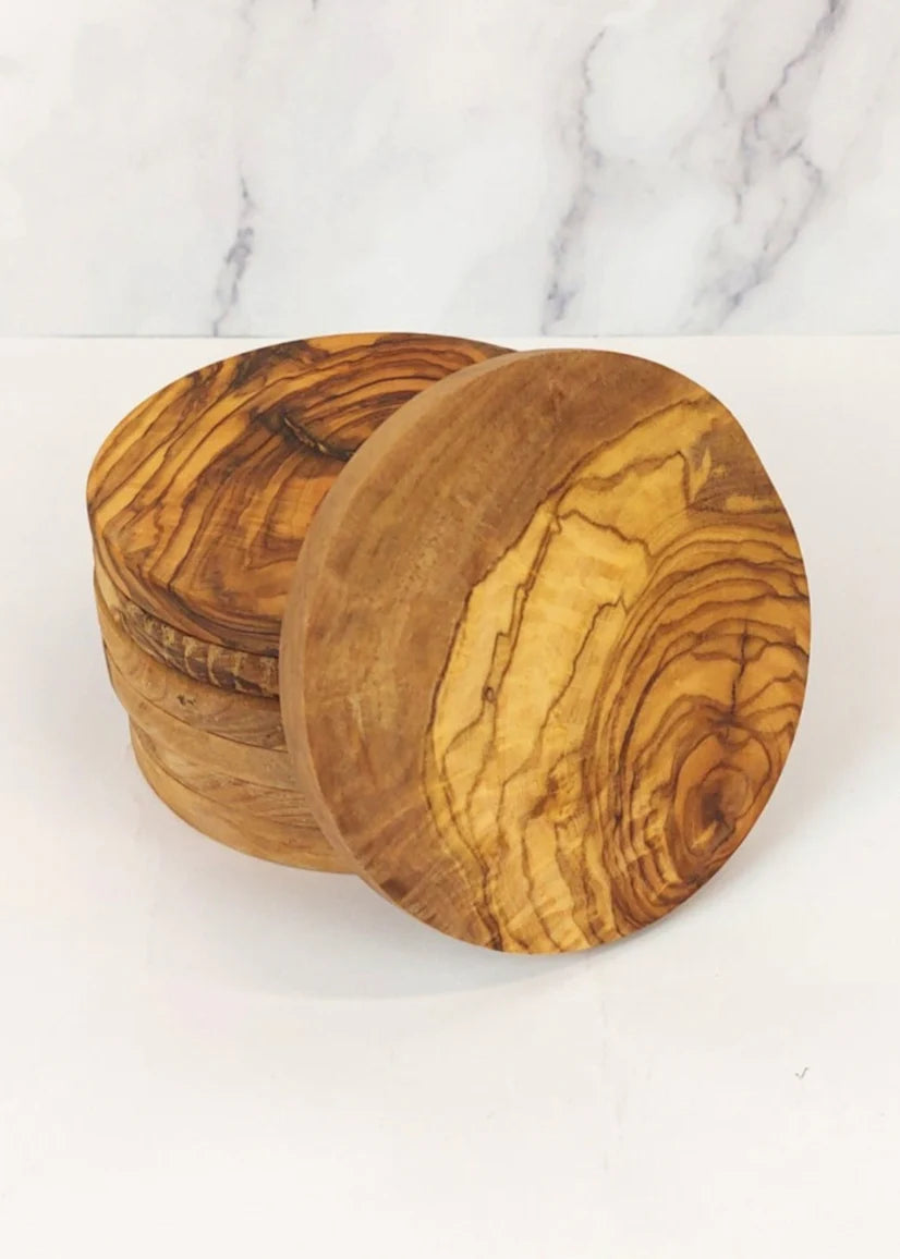 Several round olive wood coasters on a marble surface