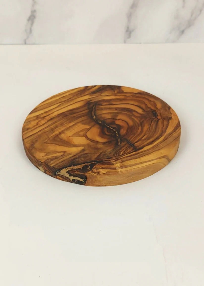 Round olive wood coaster on a marble surface