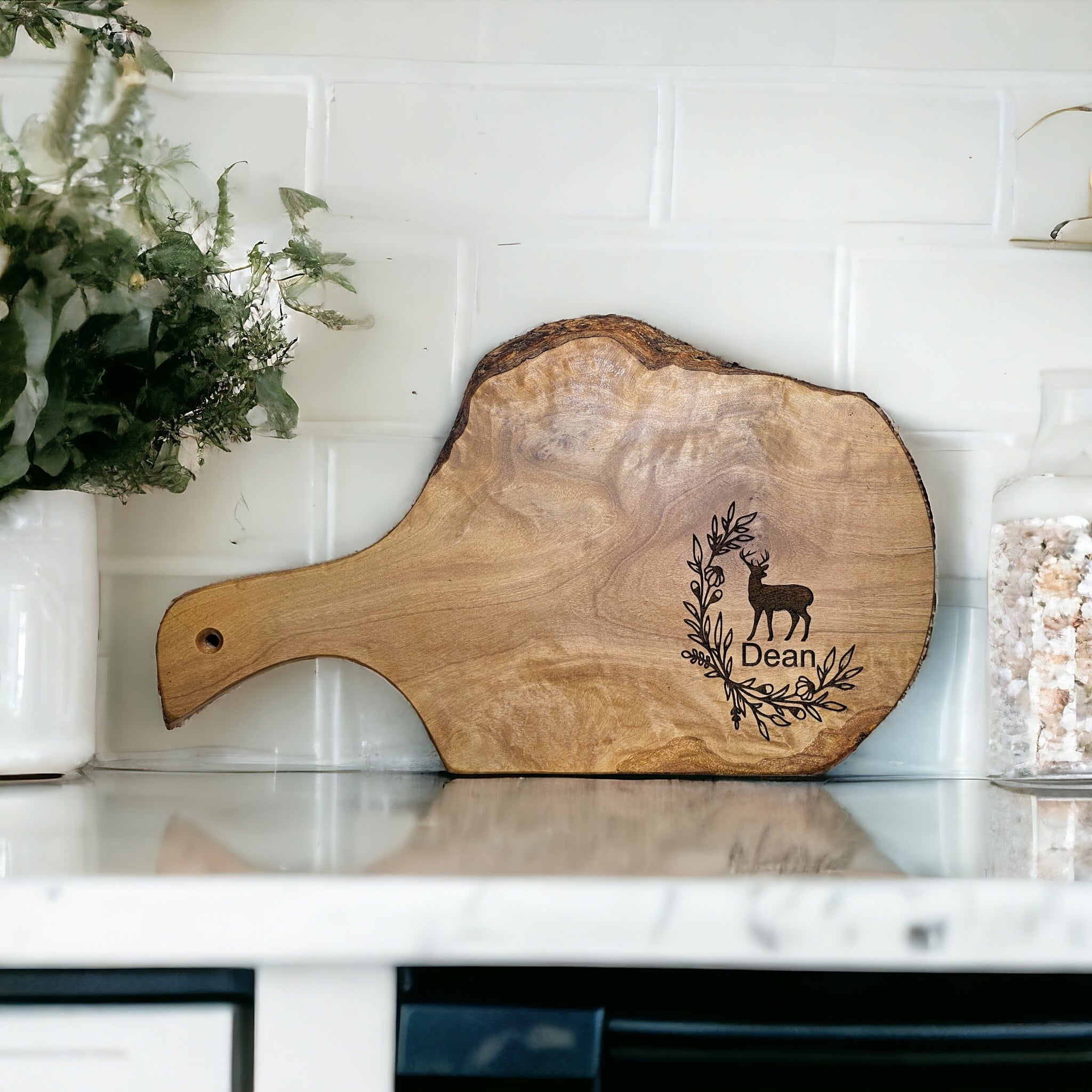 Wooden cutting board with engraved design and name on a kitchen counter.