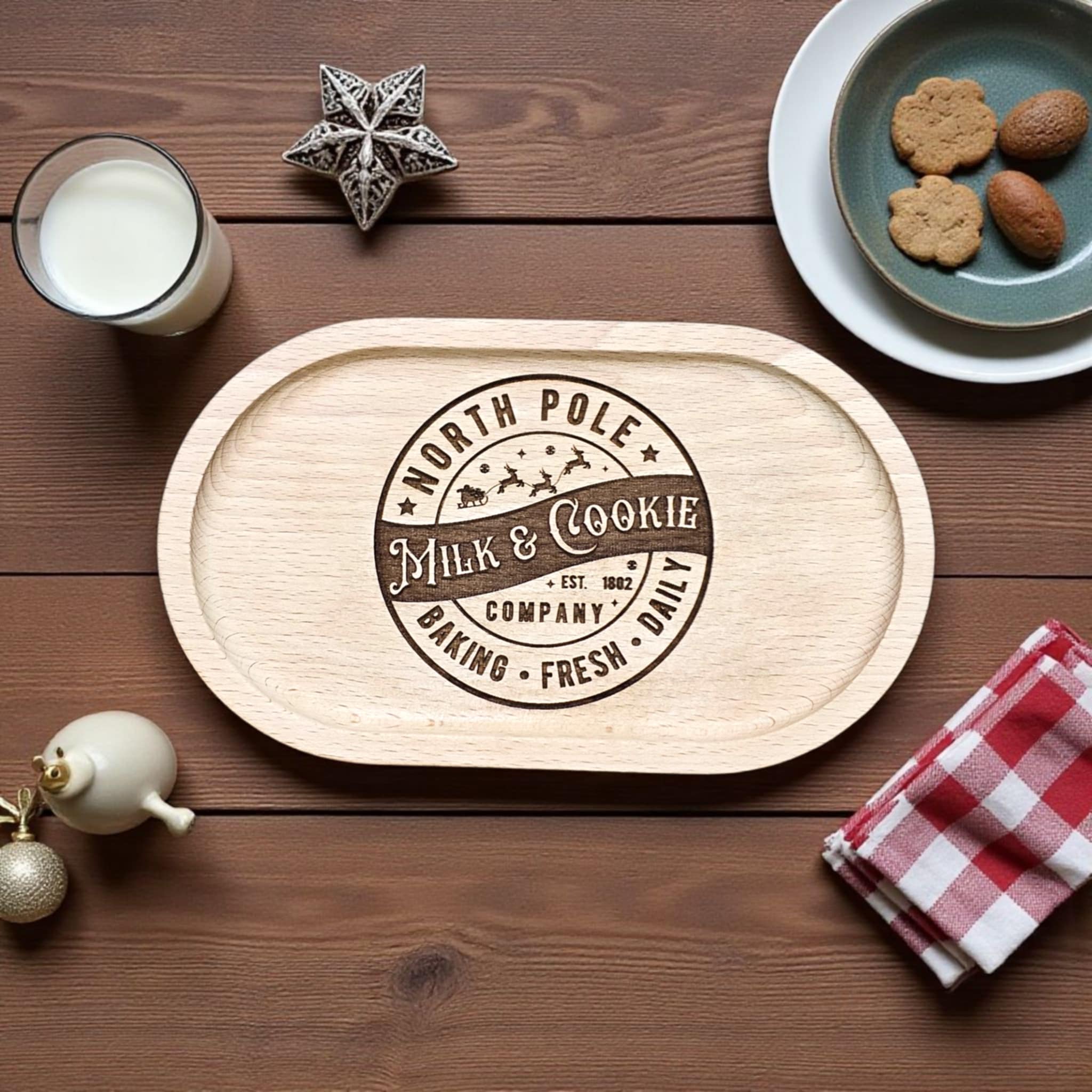 Wooden tray with 'North Pole Milk & Cookie Company' design on a wooden table with cookies and milk.