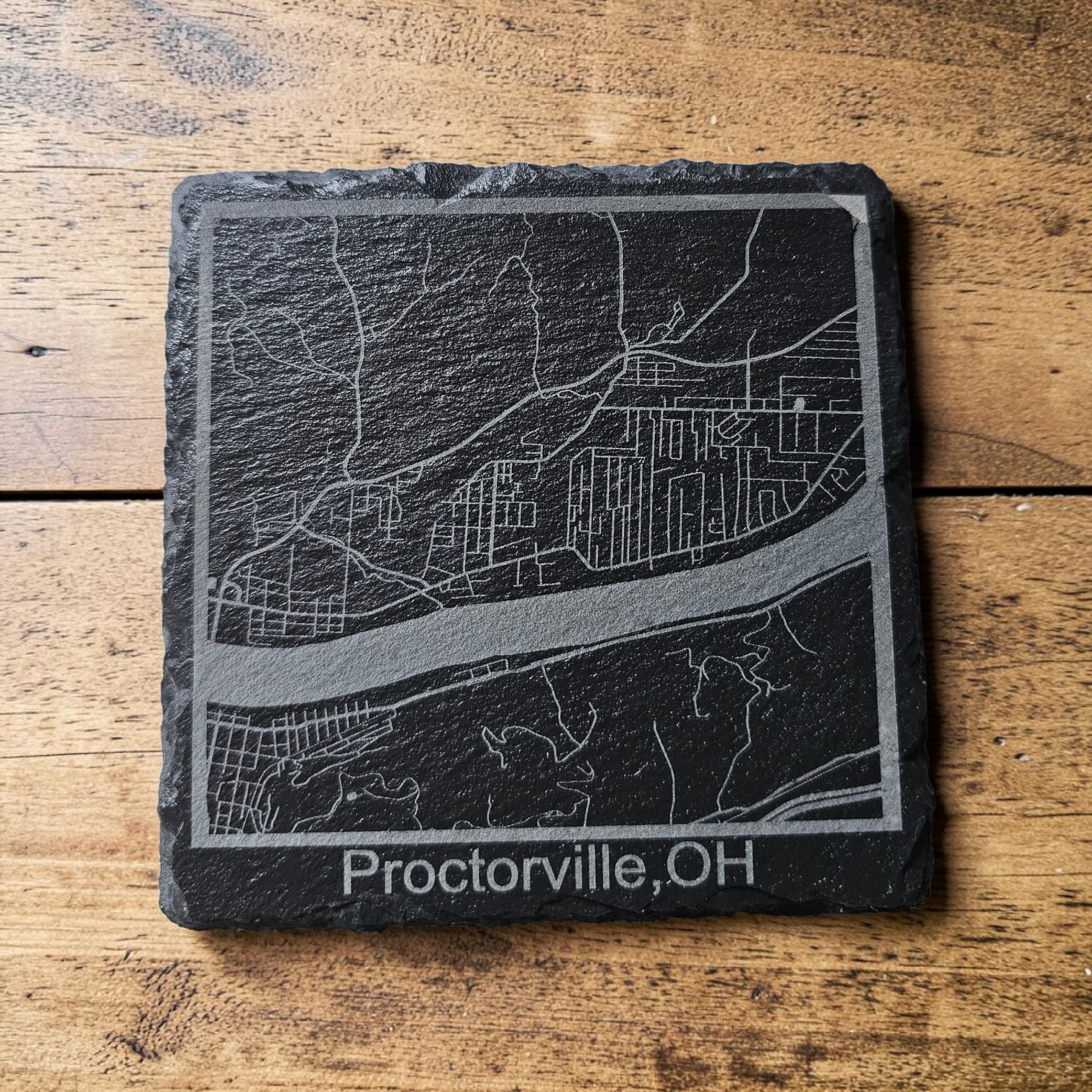Slate coaster with engraved map of Proctorville, OH on a wooden surface
