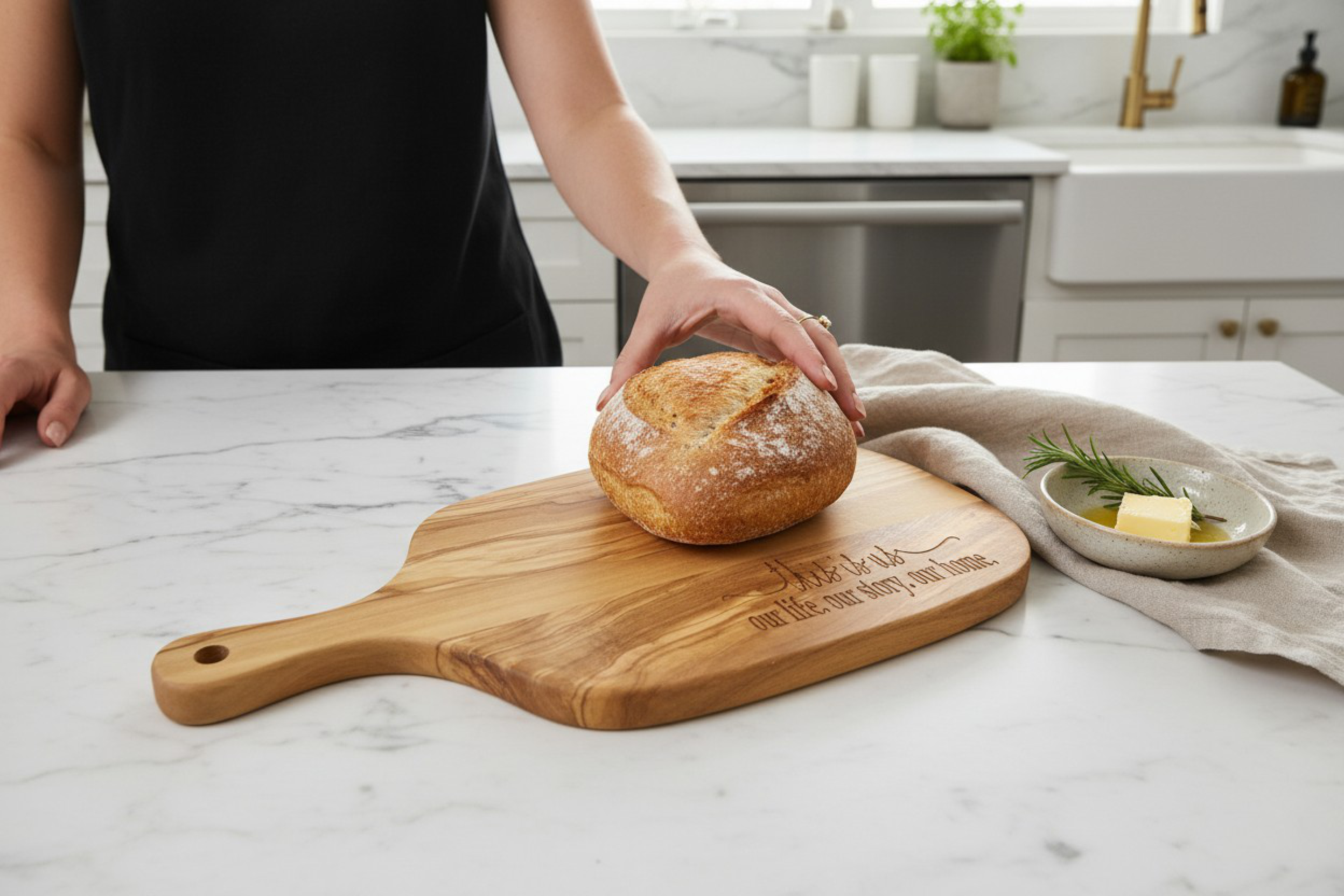 Person holding a loaf of bread on a wooden cutting board in a kitchen.