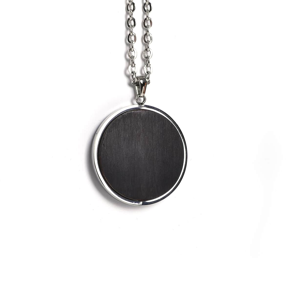 Black circular African Blackwood pendant on a silver chain against a white background